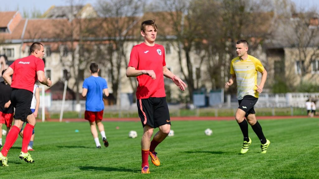 Young men practicing soccer on a sunny day at an outdoor field, focusing on exercise and teamwork.