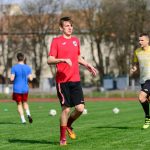 Young men practicing soccer on a sunny day at an outdoor field, focusing on exercise and teamwork.
