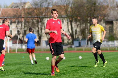 Young men practicing soccer on a sunny day at an outdoor field, focusing on exercise and teamwork.